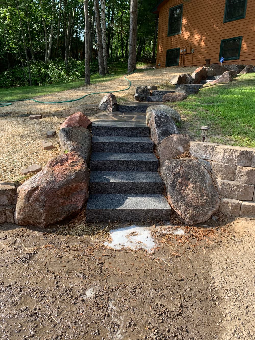 Stone steps surrounded by rocks leading to a house in a wooded area.