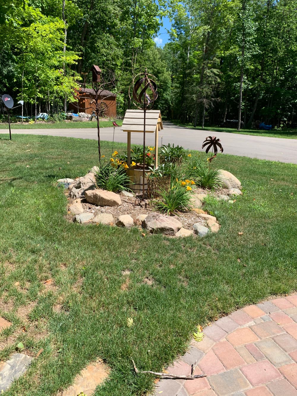 Landscape featuring a decorative birdhouse surrounded by vibrant flowers and artistic sculpture accents.