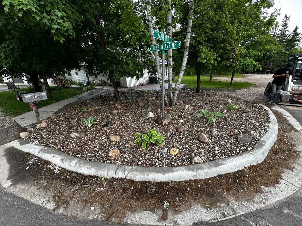 Corner landscaping with rocks and plants at Pine St and Joshua Ave intersection.