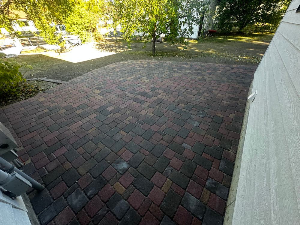 Paved outdoor patio with vibrant brick patterns surrounded by greenery.