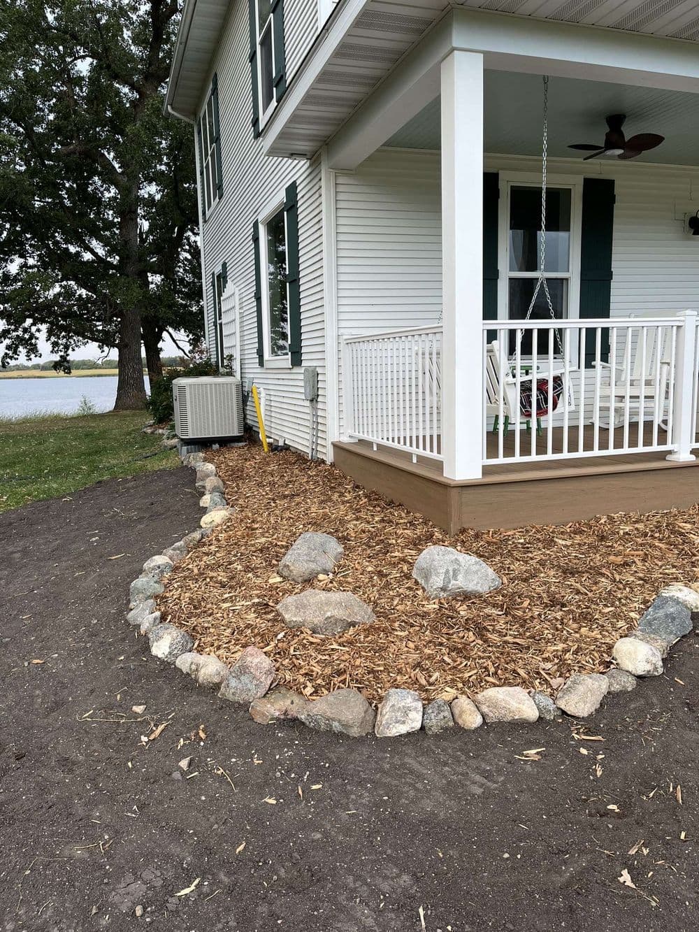 House exterior with landscaped rocks and mulch, featuring a porch and air conditioning unit.