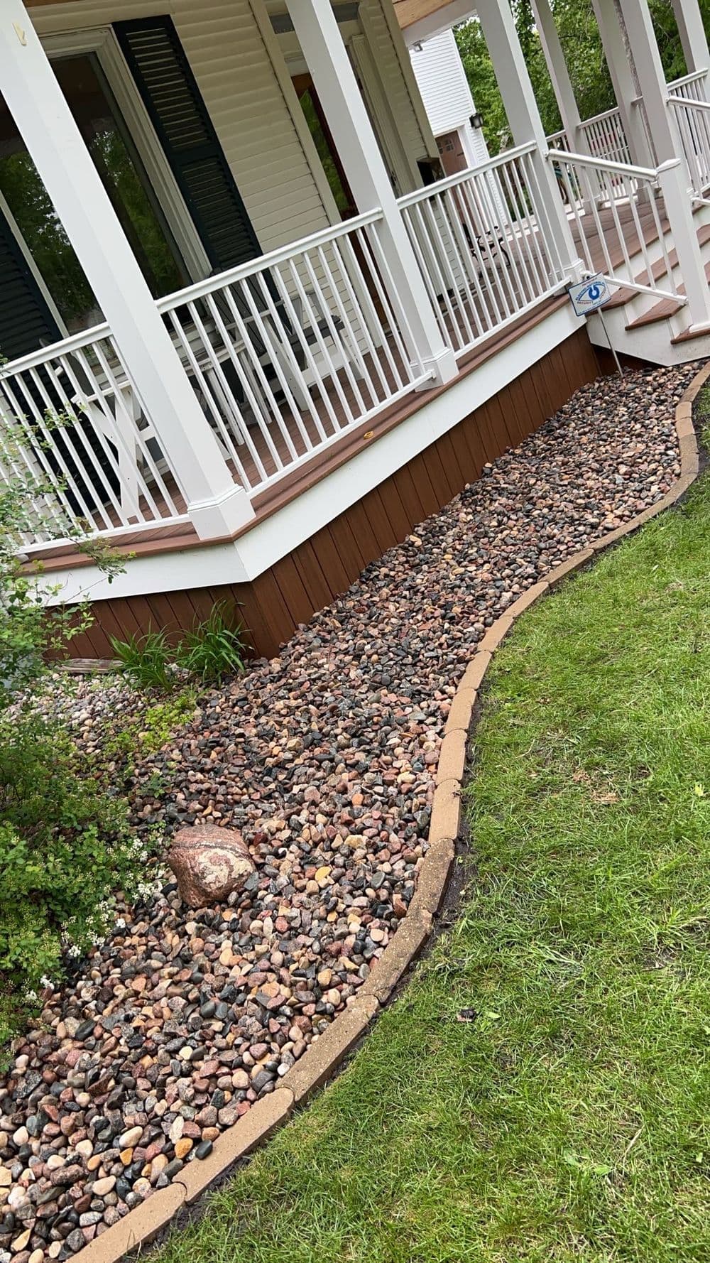 Landscaped patio with stone border, decorative rocks, and lush green grass.