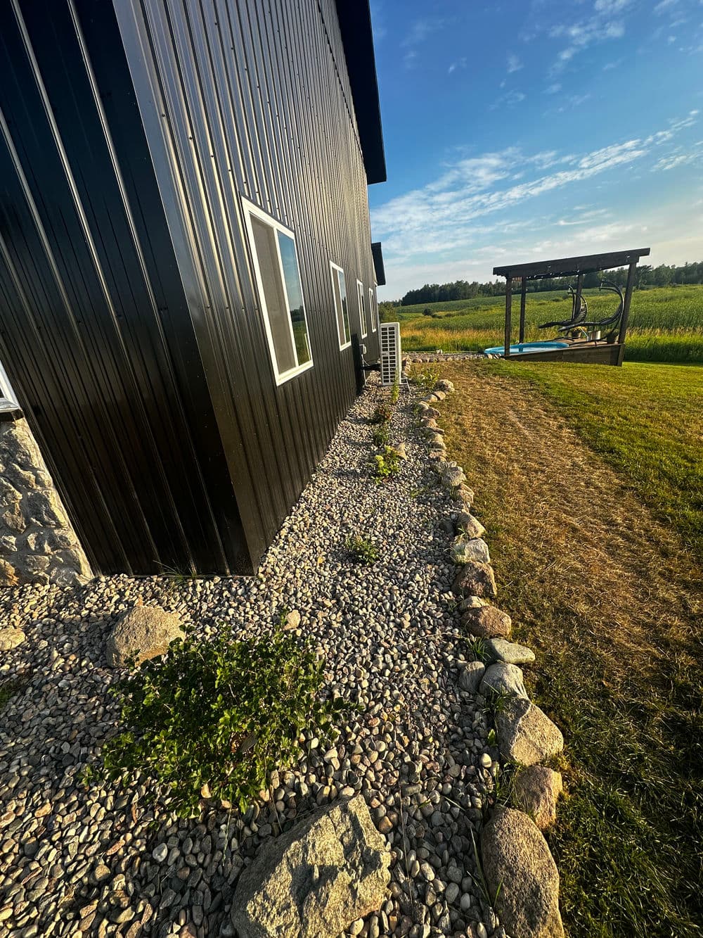 Black modern building exterior with landscaped stone borders and grassy area.
