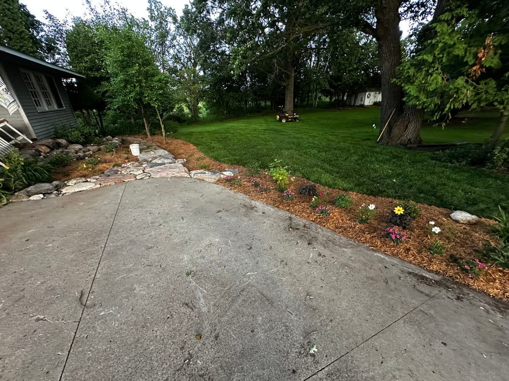 Beautiful garden landscape featuring colorful flowers, stone path, and grassy yard.