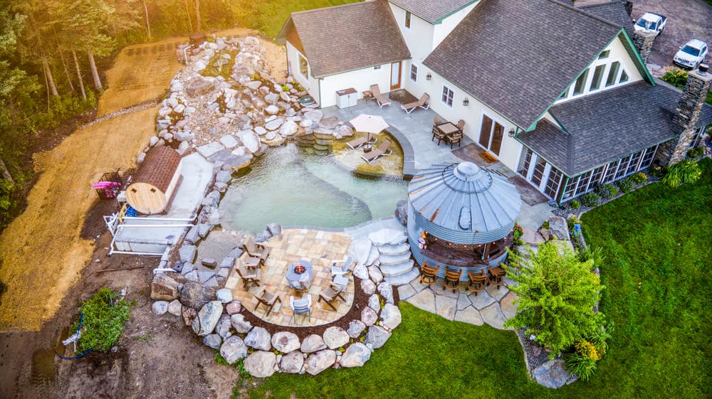 Aerial view of a luxury home with a stone pool, landscaped yard, and circular gazebo.