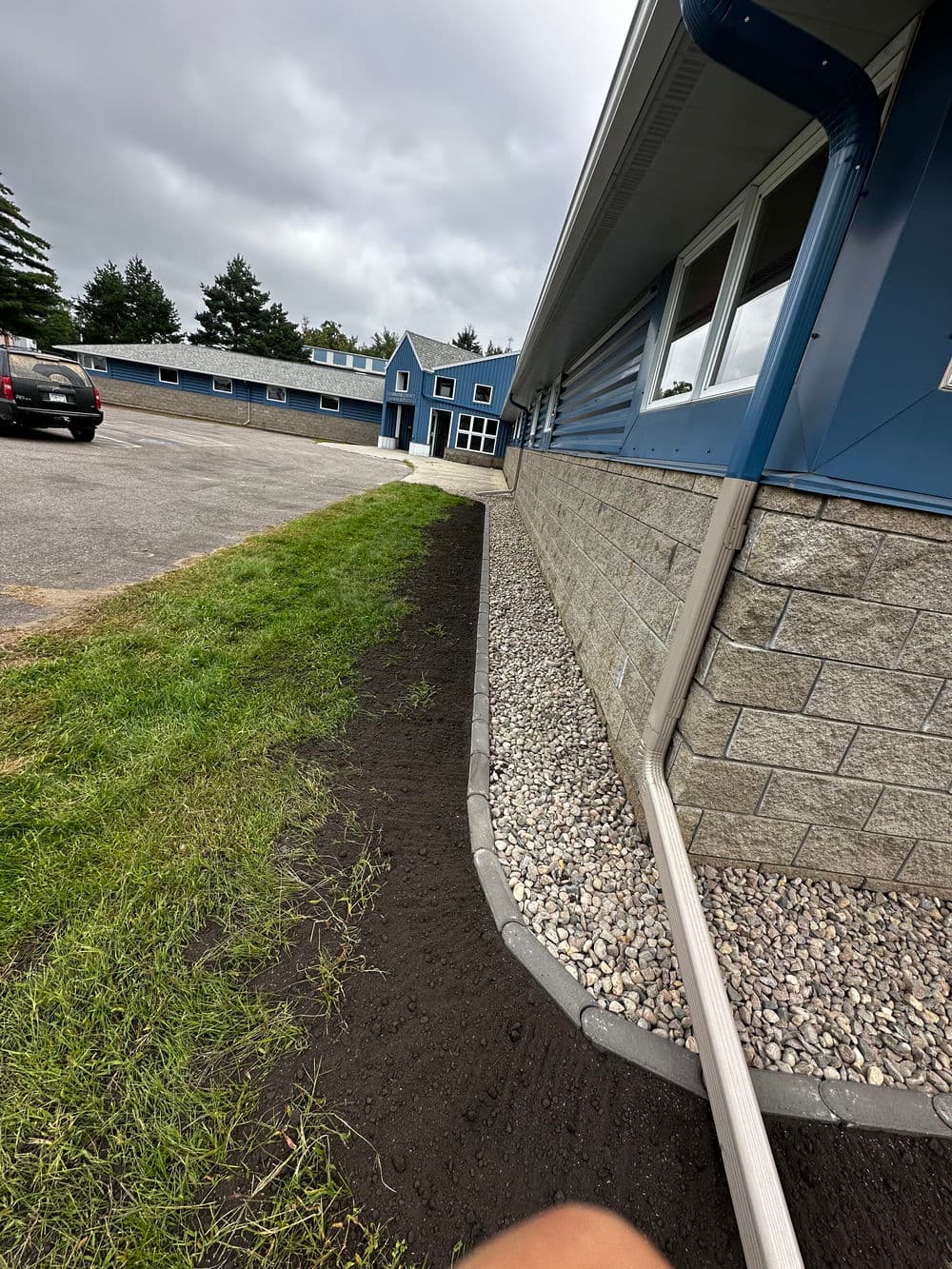 Landscape view of a building's exterior, showcasing gravel and soil alongside a paved path.