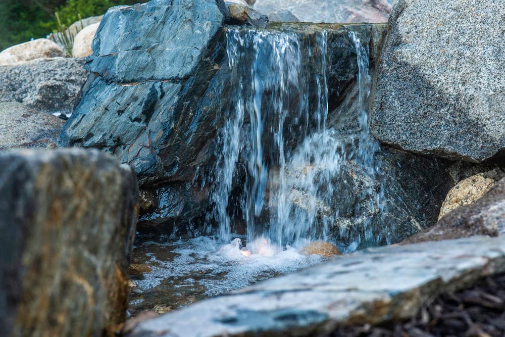 Tranquil water cascading over rocks in a natural stone waterfall setting.