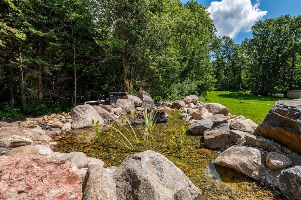 Serene garden pond surrounded by rocks and lush greenery, ideal for relaxation and nature lovers.