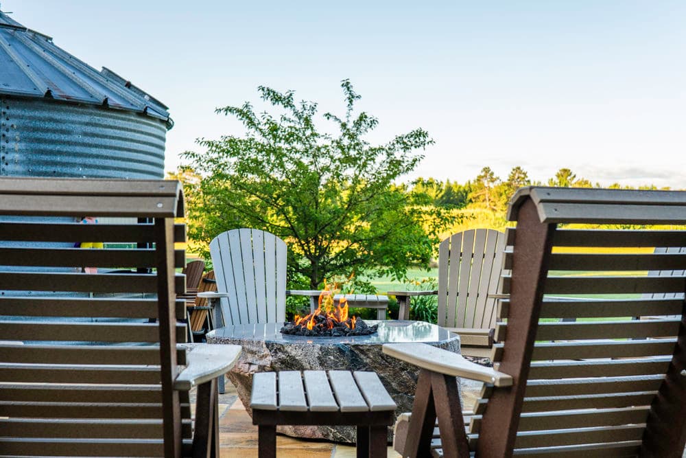 Cozy outdoor seating with a fire pit surrounded by greenery and scenic views.