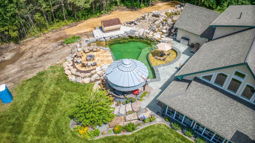Aerial view of a landscaped backyard with a pool, gazebo, and seating areas.