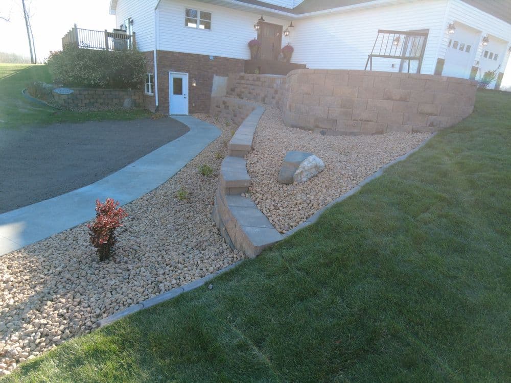 Landscaped yard featuring gravel pathway, stone steps, and a plant near a modern home.